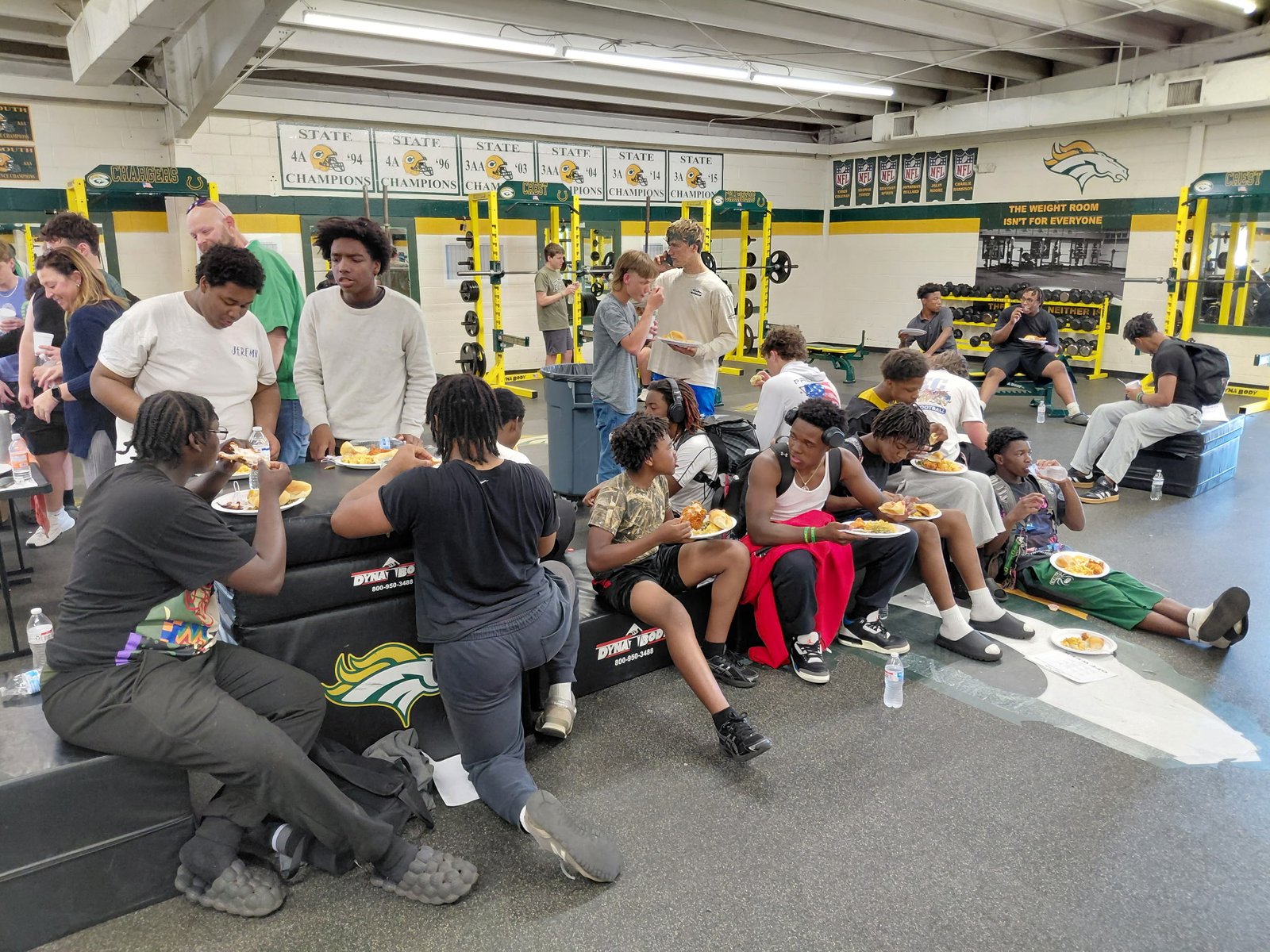Crest football players sharing a provided meal in the weight room